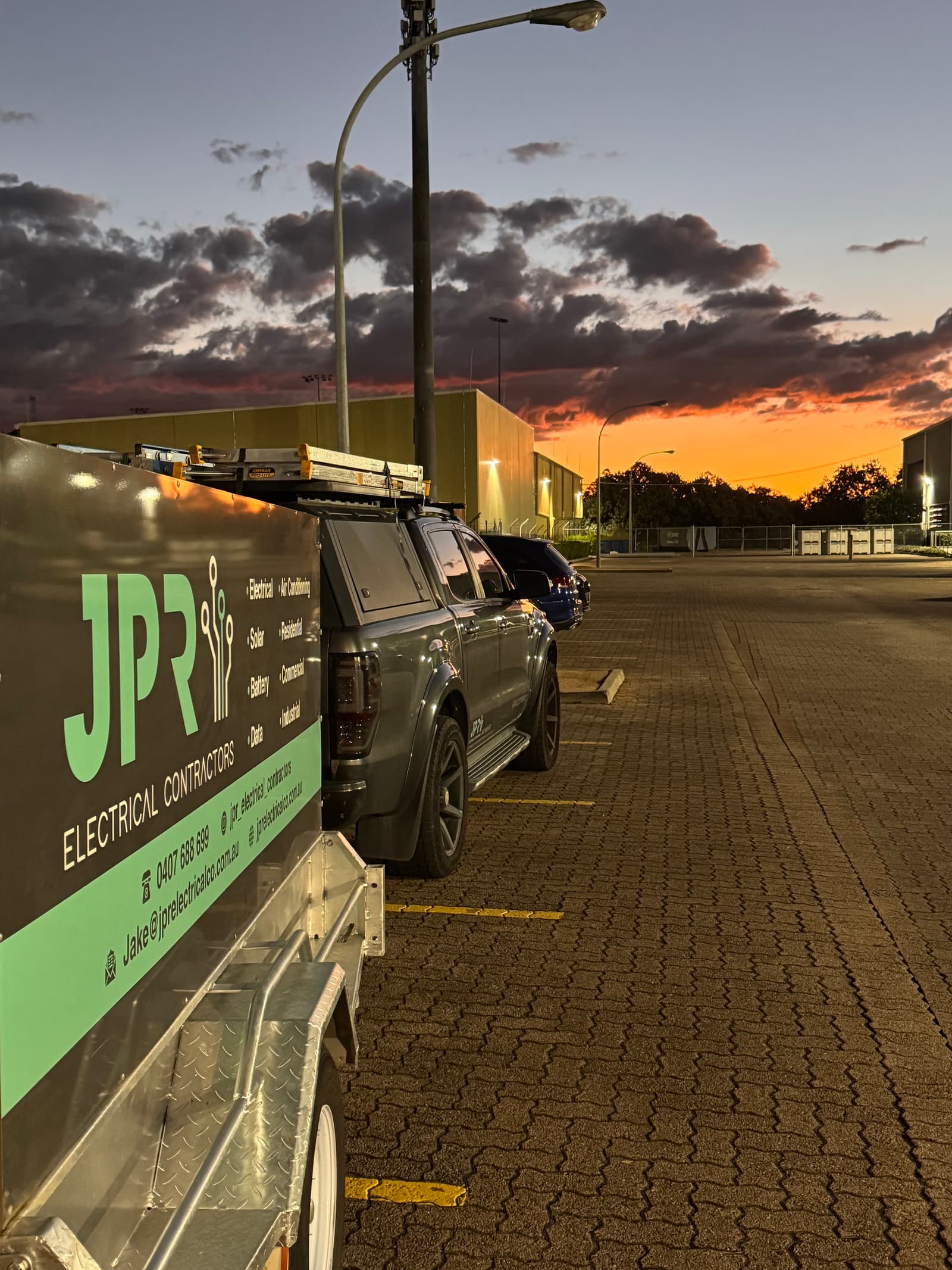 JPR Electrical work ute and trailer on site at sunset