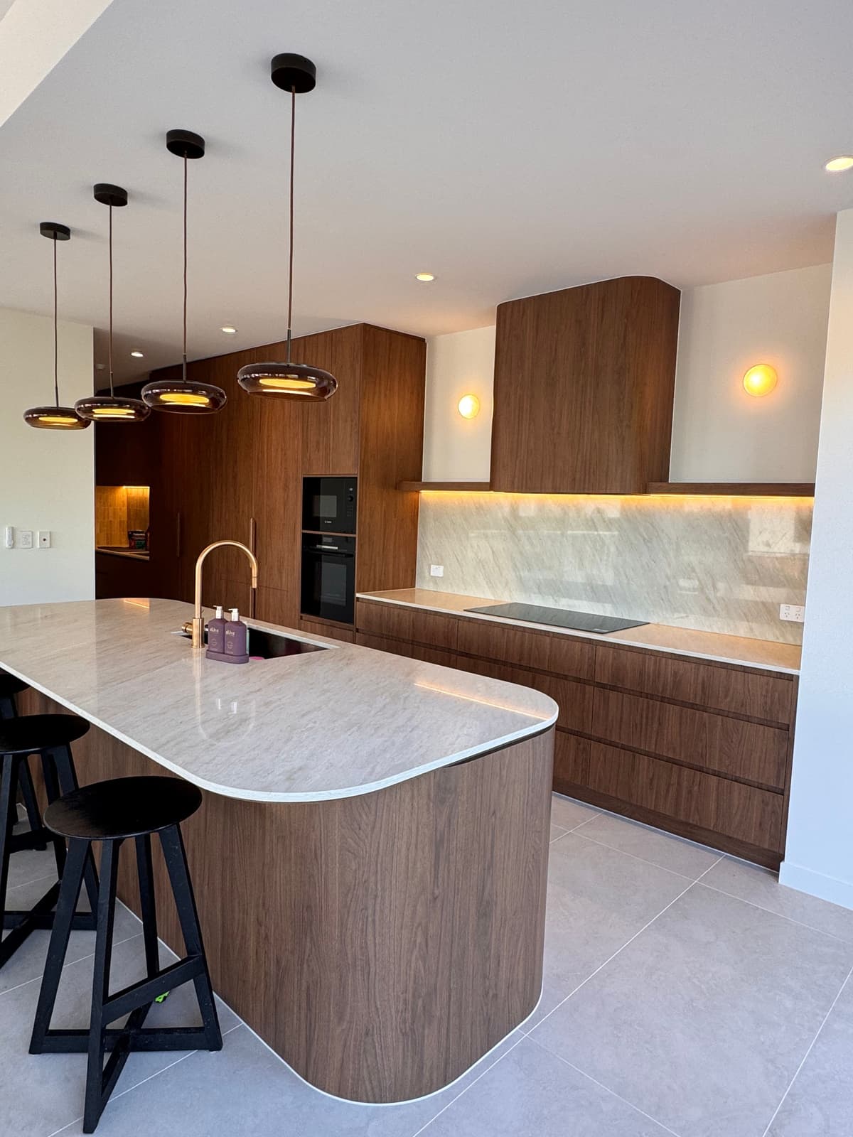 High-end residential kitchen with architectural pendant and LED strip lighting by JPR